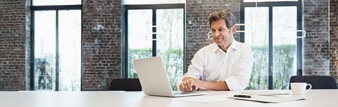Mann im weißen Hemd am Laptop