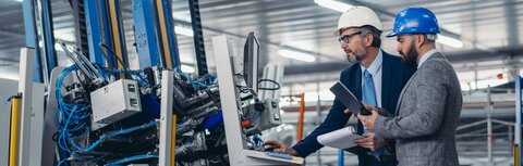 Zwei Männer mit Helmen in Produktionshalle