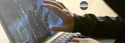 Hand eines stilisierten Hackers auf Laptop-Bildschirm