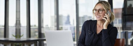 Geschäftsfrau im Gespräch mit einem Smartphone in der Hand 