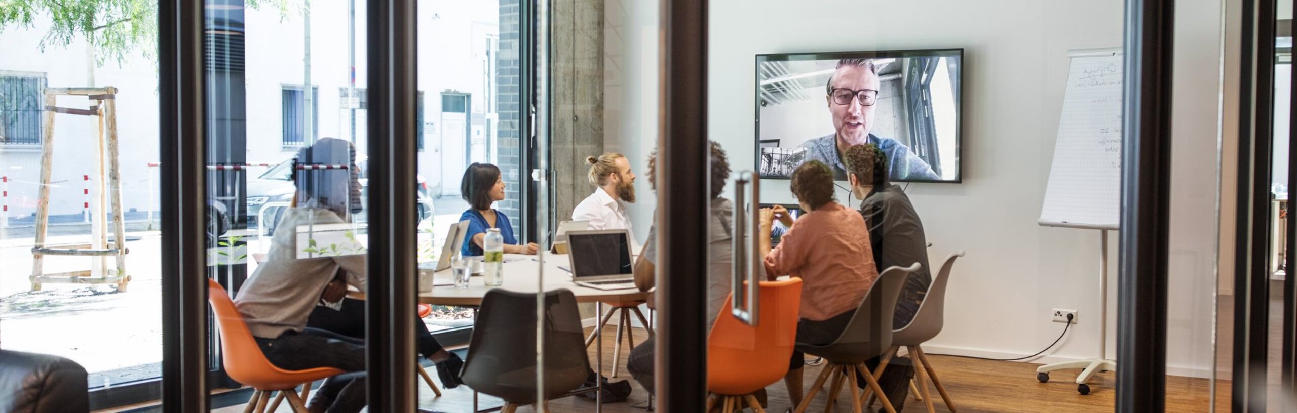 Ein gefüllter Meetingraum mit Videoübertragung zu einem anderen Standort