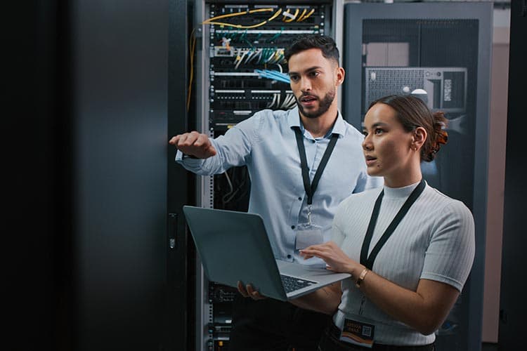 Eine Frau und ein Mann arbeiten mit einem Laptop in einem Serverraum