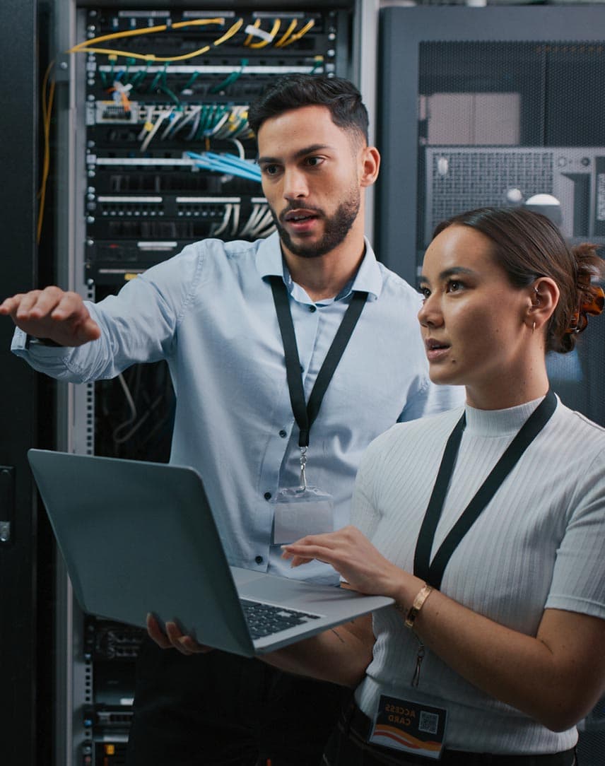 Eine Frau und ein Mann arbeiten mit einem Laptop in einem Serverraum