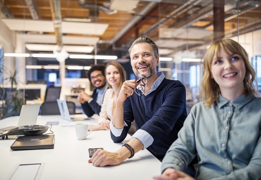 Kolleg*innen an einem Meetingtisch, die lächeln