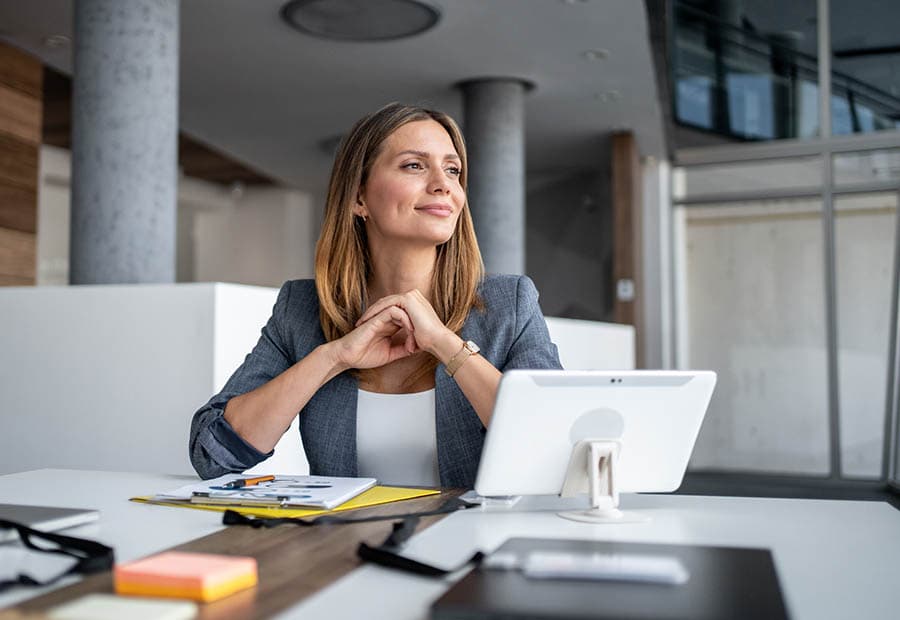 Eine Geschäftsfrau sitzt zufrieden an ihrem Arbeitsplatz.