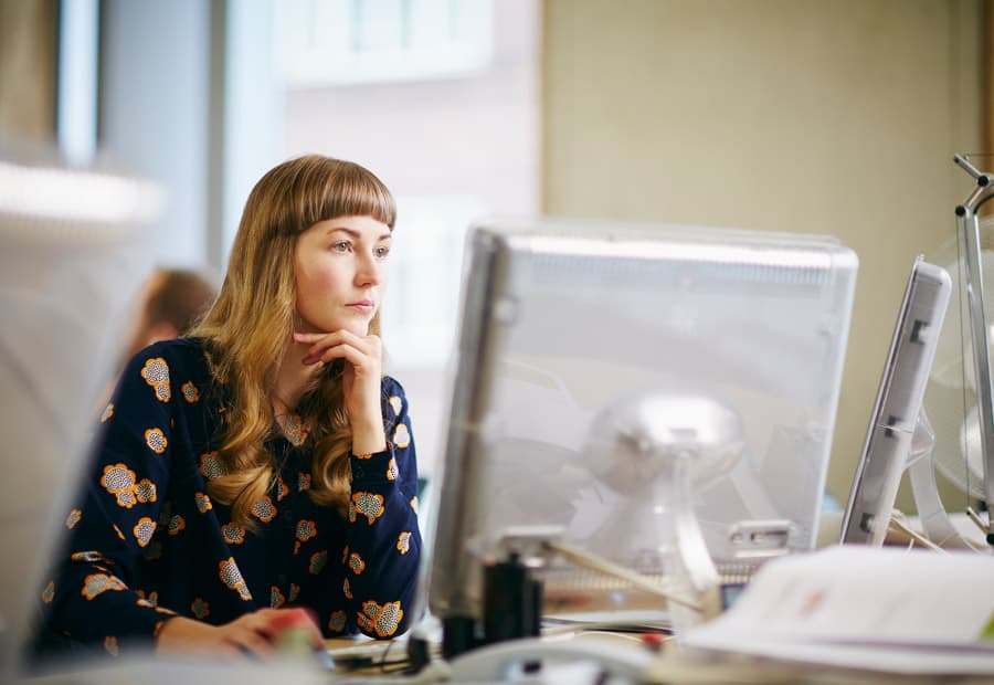 Eine Frau in einem Büro, die konzentriert auf einen Bildschirm sieht