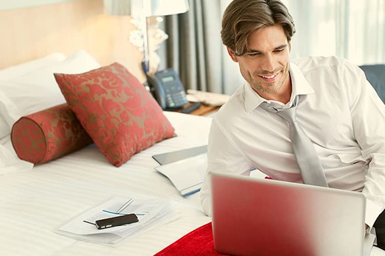 Mann im Hotelzimmer am Laptop