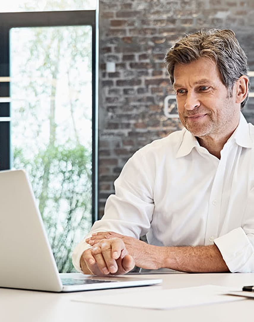 Mann im Hemd klickt auf seiner Laptoptastatur.