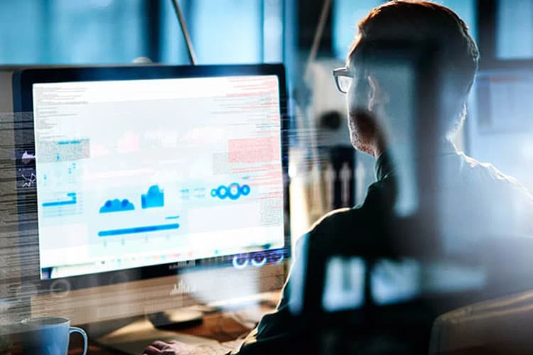 Mann sitzt am Bildschirm und programmiert etwas.