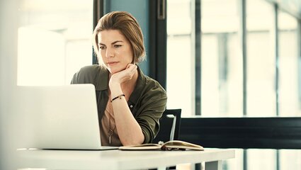Frau betrachtet interessiert Laptop-Bildschirm
