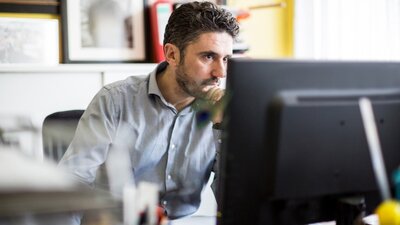 Mann schaut neugierig auf Computer-Bildschirm