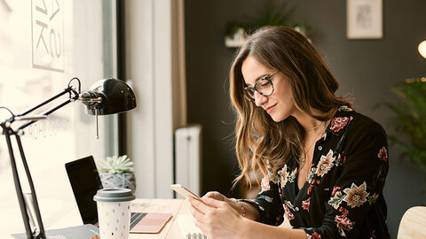 Frau im Büro schaut auf ihr Handy