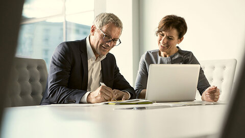 Mann und Frau im Business-Look vor Laptop