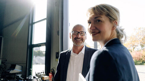 Frau und Mann im Business-Look lächeln in die Kamera