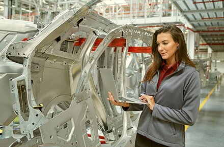 Frau am Laptop in Produktionshalle
