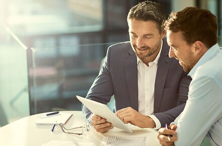Zwei Männer im Business-Look schauen auf Tablet