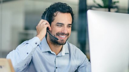 Mann im Büro mit Headset vor einem Bildschirm