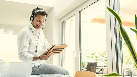 Mann mit Tablet in der Hand telefoniert mit Headset