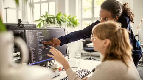 Zwei Frauen schauen gemeinsam auf einen Computer-Bildschirm