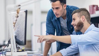 Ein Mann zeigt einem Kollegen etwas am Computer-Bildschirm