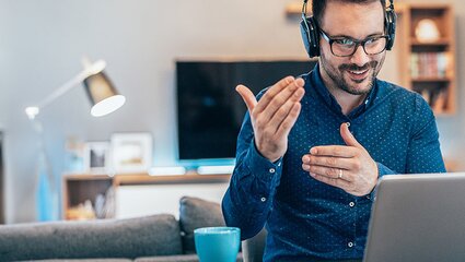 Mann mit Headset erklärt etwas vor dem Laptop