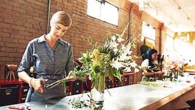 EWE business Grünstrom basis Eine Blumenhändlerin schneidet Blumen in einem Blumengeschäft.
