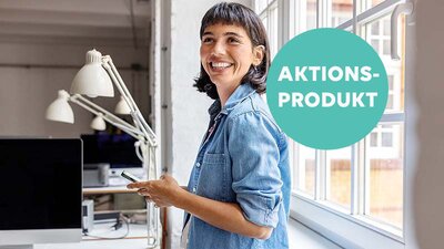 EWE business Grünstrom Eine lächelnde Frau steht in einem Büro neben einem Fenster.